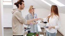 Empat tangan yang saling menumpuk di atas tumpukan koin dan uang kertas, melambangkan semangat kolaborasi dan investasi bersama dalam membangun sebuah usaha. Ini menggambarkan bagaimana setiap kontribusi, besar maupun kecil, dapat bersatu membentuk fondasi finansial yang kuat bagi sebuah bisnis yang menjanjikan.