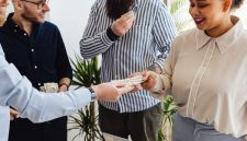 Sekelompok orang yang bersemangat berkolaborasi di meja diskusi, tampak sedang merancang strategi bisnis mereka dengan penuh antusiasme. Tumpukan koin di tengah menunjukkan konsep patungan modal sebagai fondasi utama untuk mewujudkan impian usaha bersama.