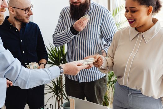 Sekelompok orang yang bersemangat berkolaborasi di meja diskusi, tampak sedang merancang strategi bisnis mereka dengan penuh antusiasme. Tumpukan koin di tengah menunjukkan konsep patungan modal sebagai fondasi utama untuk mewujudkan impian usaha bersama.