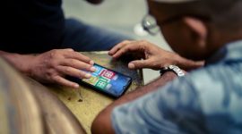 Seorang anggota koperasi dari daerah pedesaan tengah mengakses aplikasi koperasi digital melalui ponsel pintarnya, menunjukkan kemudahan akses layanan keuangan dan pasar bagi masyarakat di pelosok. Gambar ini merepresentasikan bagaimana digitalisasi koperasi menjembatani kesenjangan geografis, memberdayakan ekonomi lokal, dan meningkatkan partisipasi anggota dalam ekosistem digital.
