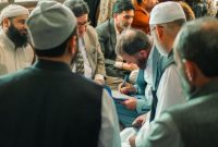 Beberapa anggota koperasi syariah sedang berdiskusi mengenai rencana pengembangan usaha, menunjukkan semangat kebersamaan dalam membangun ekonomi yang berlandaskan prinsip syariah. Pertemuan ini mencerminkan transparansi dan partisipasi aktif anggota dalam pengambilan keputusan finansial mereka.