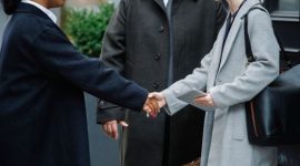 Dua orang berjabat tangan di atas meja dengan dokumen keuangan, melambangkan kesepakatan bagi hasil yang transparan dan saling menguntungkan dalam kemitraan bisnis. Gambar ini menangkap esensi kolaborasi dan kepercayaan dalam sistem ekonomi berbagi.