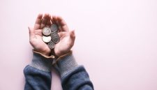 Sejumlah tangan secara simbolis saling menggenggam koin, melambangkan semangat gotong royong dan kebersamaan dalam praktik simpan pinjam. Gambar ini merepresentasikan bagaimana setiap individu berkontribusi untuk menciptakan kekuatan finansial kolektif yang saling mendukung.