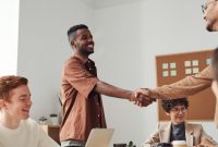 Anggota koperasi syariah sedang berinteraksi dalam sebuah pertemuan, menunjukkan semangat kebersamaan dan kolaborasi. Ilustrasi ini merepresentasikan model ekonomi kerakyatan yang mengedepankan nilai-nilai syariah.