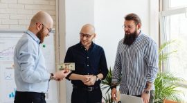 Beberapa tangan saling menyatukan lembaran uang di atas meja, melambangkan konsep patungan modal yang efektif dalam memulai sebuah usaha. Kolaborasi finansial ini menunjukkan semangat kebersamaan dan pembagian risiko untuk mencapai tujuan bisnis yang sama.